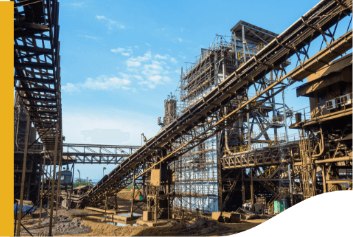 The image shows an industrial facility with multiple conveyor belts and metal structures. The sky is clear with some scattered clouds. There are no visible people or vehicles in the image. The facility appears to be involved in material handling or processing, likely related to mining or manufacturing.